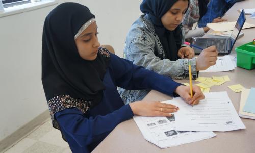 Student writing at table