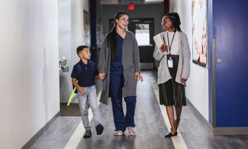 Mother and son walking down the hall with a teacher