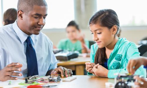 Teacher working with a student on electricity experiment