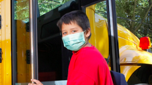 Boy in face mask getting on bus