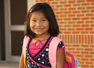 young girl smiling at camera and wearing a backpack