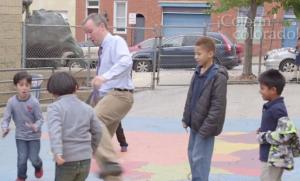 one man playing a sport with children on a concrete play area