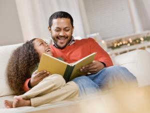 Father and daughter reading a book on couch