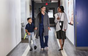 Mother and son walking down the hall with a teacher