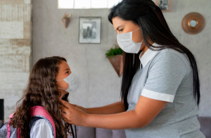 Mother saying good-bye to child before school wearing face masks