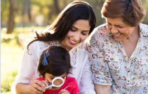 Mother and grandmother with child using magnifying glass