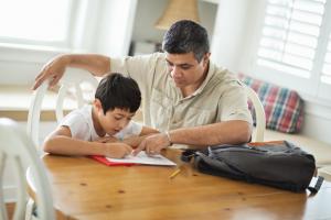 Father helping son with homework at table