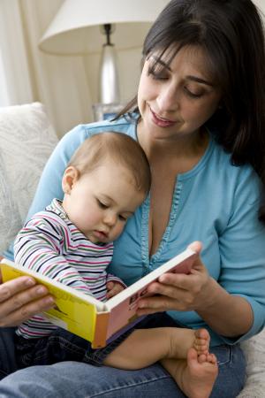 A woman reading to a baby in her lap.