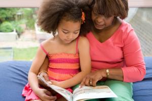 A woman reading to a girl in her lap.