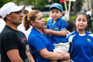 three adults standing in a line. one woman is holding a child.