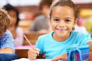 Young girl looking at camera and holding a pencil