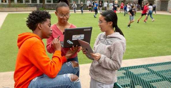 Group of middle school students with a laptop outside