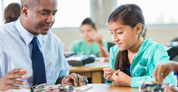 Teacher working with a student on an electricity experiment