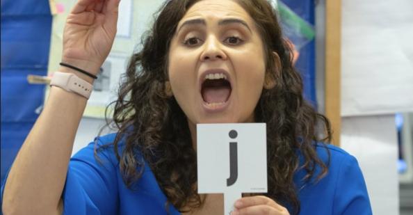 Teacher holding up card with the letter "j"