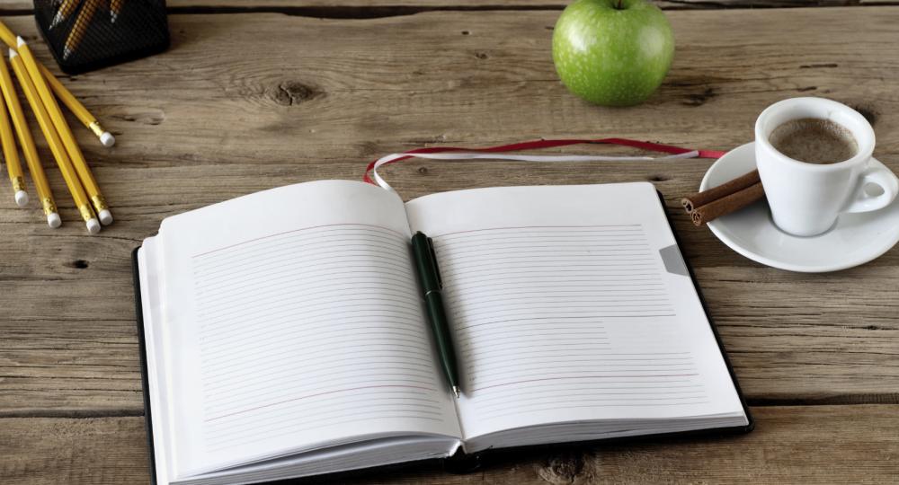 Notebook, pen, coffee, and apple on table